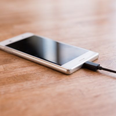 Mobile smart phone charging on wooden desk